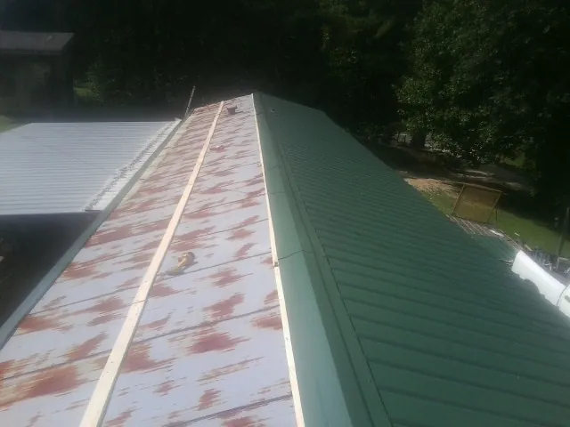 Old rusted panels beside newly installed green metal roofing — Wind Damage Roof Repair by Roofing Brothers in Lake Placid