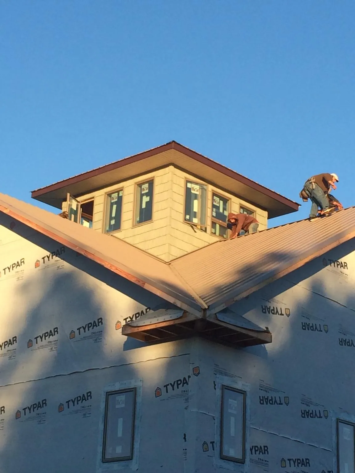 Roofers working around a rooftop cupola on a new metal roof at sunset — Roof Waterproofing in Lake Placid by Roofing Brothers